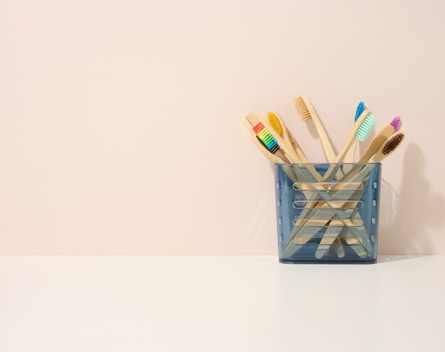 Brosses à dents en bois dans un gobelet en plastique sur une table blanche. Fond beige, zéro déchet. Espace de copie