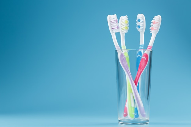 Brosses à dents colorées dans un verre sur une surface bleue