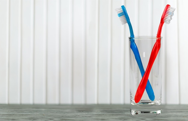 Brosses à dents dans un verre sur une table en bois