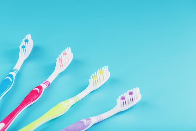 Brosses à dents de différentes couleurs d'affilée sur une surface bleue