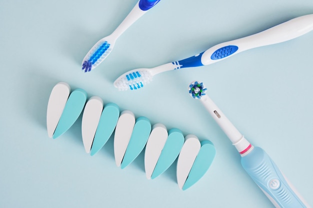 Brosses à dents électriques et en plastique sur fond bleu dont les brosses sont plus efficaces pour nettoyer la cavité buccale et plus écologiques