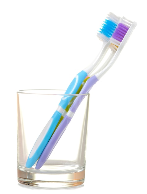 Brosses à dents multicolores dans un bécher en verre sur un blanc isolé. Hygiène buccale.