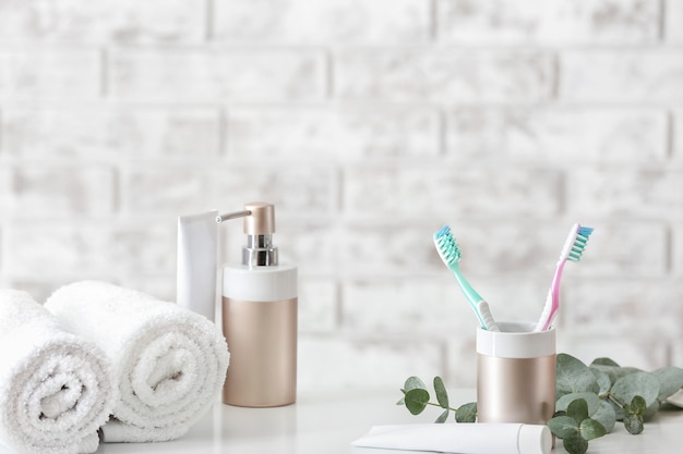 Brosses à dents avec de la pâte, des serviettes et du savon sur la table dans la salle de bain