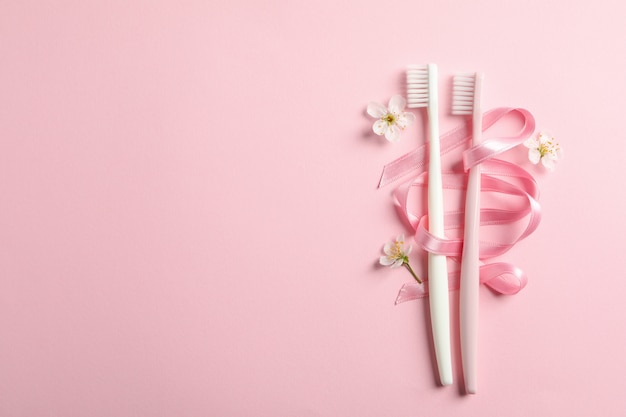 Brosses à dents, ruban et fleurs sur surface rose