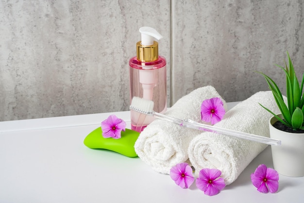Brosses à dents, savon et deux serviettes. Maison d'aromathérapie aux fleurs roses. Photo de haute qualité