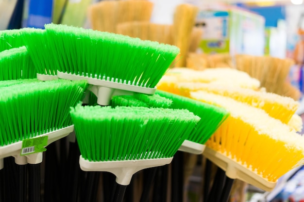 Brosses en plastique pour nettoyer les locaux Assortiment de balais multicolores dans le magasin Gros plan