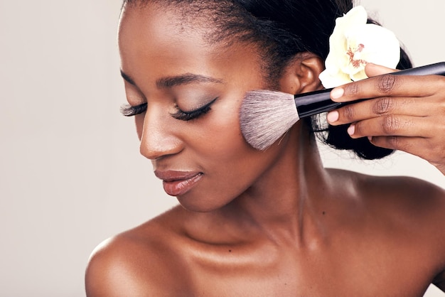 Brossez le maquillage élégant et le visage d'une femme noire avec une maquette en studio avec un outil d'application cosmétique.