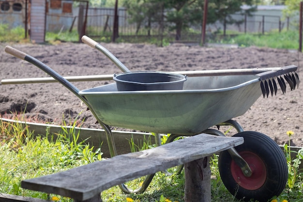 Brouette de jardin en métal gris avec deux poignées et une roue La brouette est dans le jardin ou le jardin Brouette du jardinier dans la cour Nettoyage du jardin