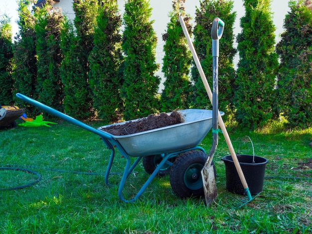 Brouette pelle dans l'herbe de jardin avec concept de jardinage de seau