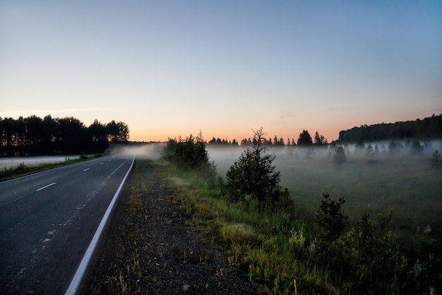 Brouillard au sol près de la route au coucher du soleil