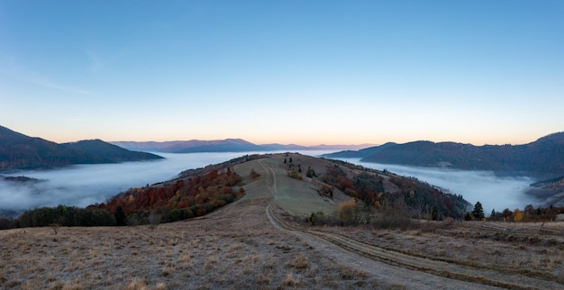 Brouillard épais parmi les sommets des hautes montagnes d'automne au lever du soleil