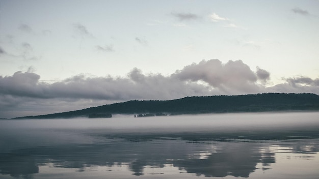 Photo brouillard sur le lac avec une montagne en arrière-plan