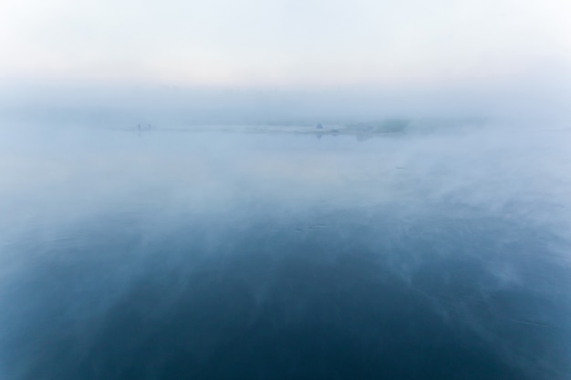 Brouillard sur la rivière. Brume matinale sur la rivière avec le rivage à l'horizon, fond bleu flou.