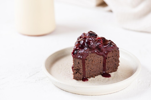 Brownie au chocolat aux cerises sur une plaque blanche. Sans sucre, sans gluten, sans lactose, végétalien.