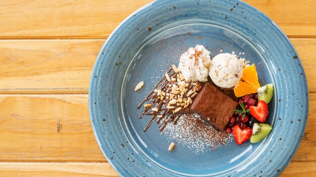 Brownie au chocolat avec crème glacée et mélanger les fruits dans une assiette bleue.