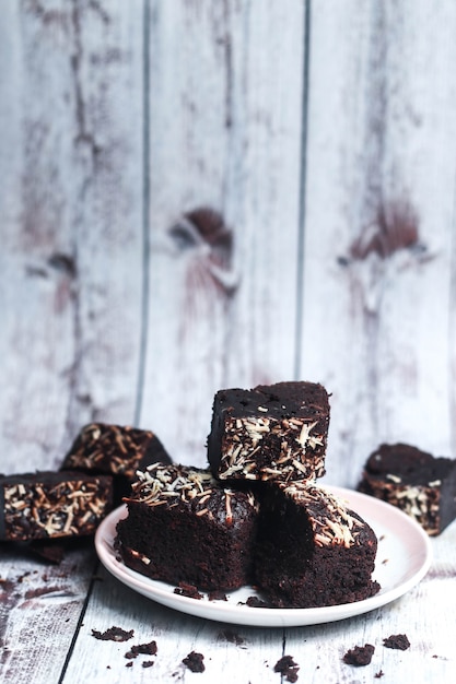 Brownies au chocolat sur une assiette et avec des morceaux sur une table en bois