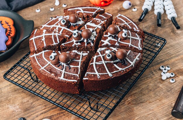 Brownies de toile d'araignée au chocolat avec des araignées en bonbons, friandises maison pour Halloween sur fond de bois rustique