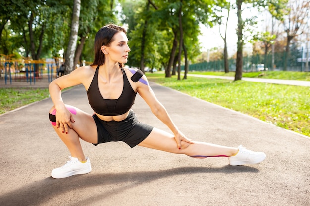 Bruette fille flexible avec un corps parfait s'échauffant à l'extérieur