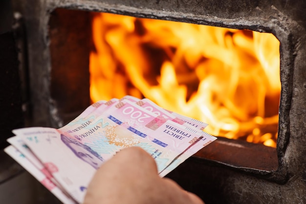 Brûler de l'argent dans une chaudière à combustible solide comme symbole des dépenses élevées pour chauffer la maison