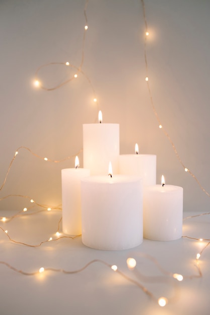 Brûler des bougies blanches entourées de guirlandes lumineuses sur fond gris