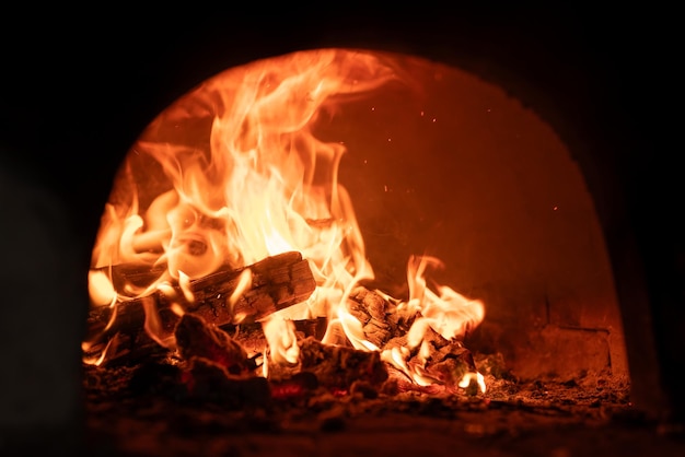 Brûler du bois de chauffage dans le four dans un chalet Poêle traditionnel à la campagne cuisant des aliments et chauffant les concepts de la maison