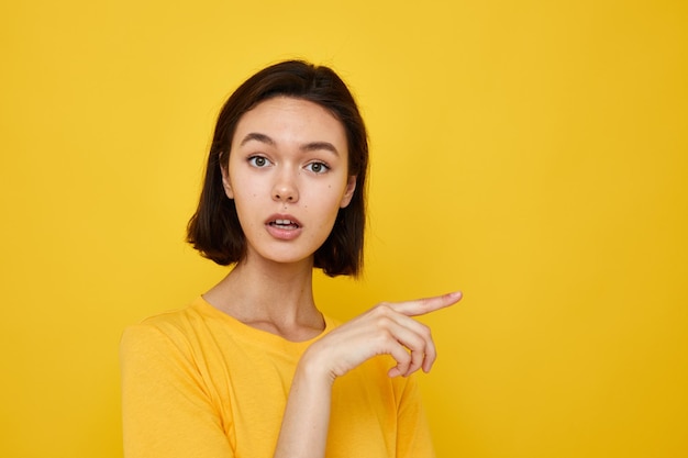 Brune aux cheveux courts dans un t-shirt jaune style jeunesse fond isolé décontracté