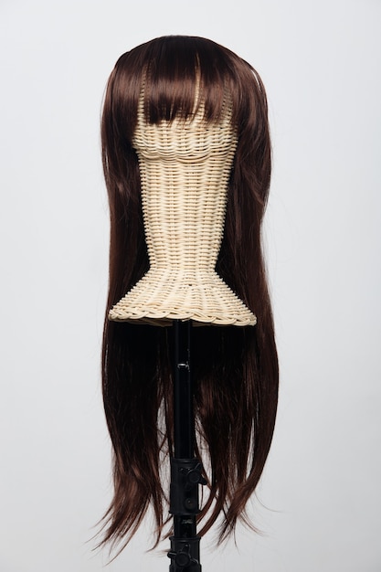 Brune brune longue perruque de cheveux raides sur la tête de mannequin en rotin sur fond blanc isolé, montre de nombreux angles de vague de style de cheveux et point de vue lumineux