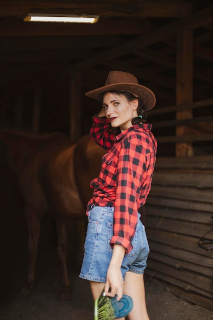 Photo une brune en cow-boy à l'écurie.