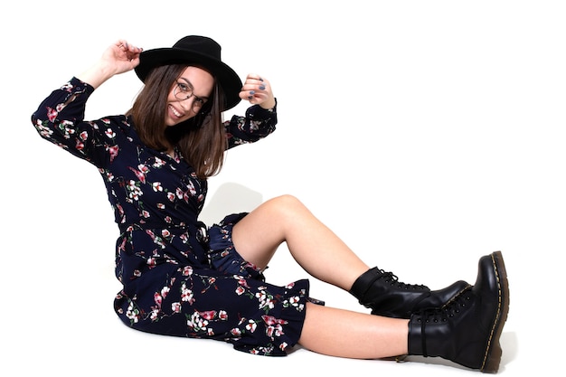 Une brune dans une longue robe à fleurs avec un chapeau pose pour la caméra