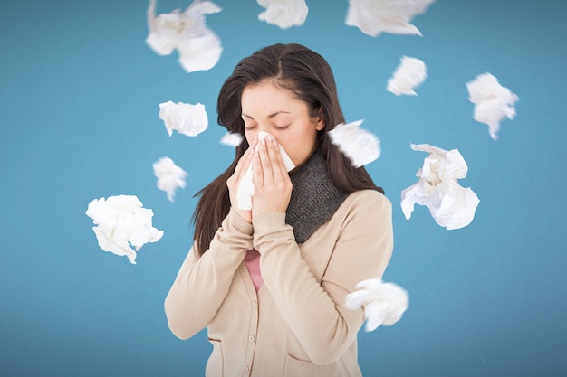 Brune malade soufflant son nez sur fond bleu