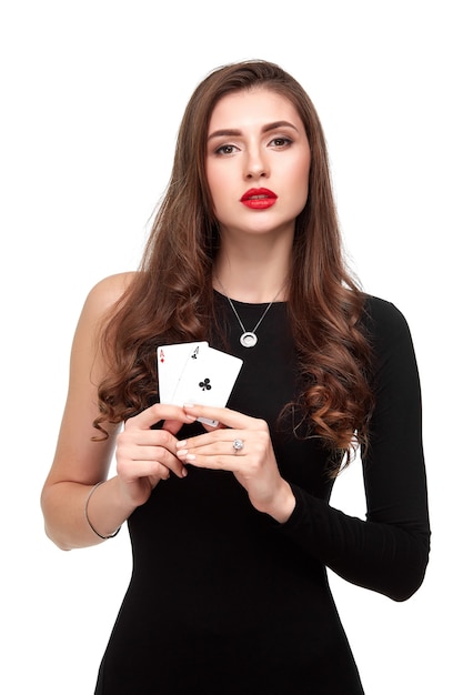 Brune sexy aux cheveux bouclés posant avec deux cartes d'as dans ses mains isolement de concept de poker sur fond blanc...