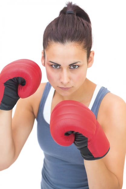 Brune sportive sévère portant des gants de boxe rouges