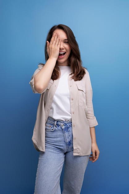 Brunet jeune femme brune habillée décontractée mignonne souriante sur fond bleu