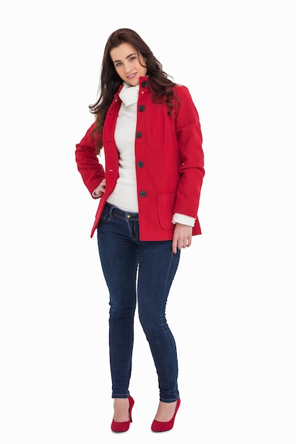 Brunette de beauté posant en manteau rouge et talons