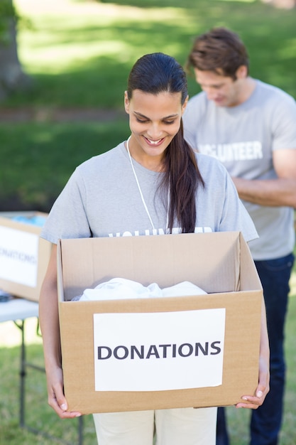 Brunette bénévole heureuse tenant la boîte de donation