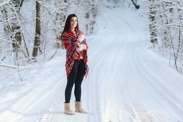 Brunette dans une couverture dans la forêt d'hiver