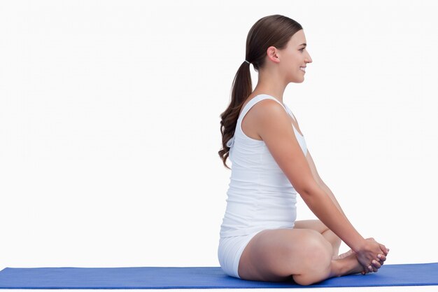 Brunette femme assise sur un tapis de yoga