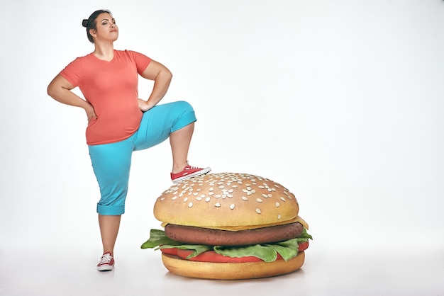 Brunette femme dodue drôle a mis sa jambe à un énorme sandwich