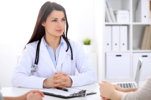 Brunette femme médecin parlant à un patient à l'hôpital.