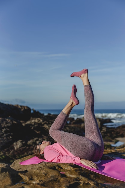 Brunette femme pratiquant le yoga sur la plage