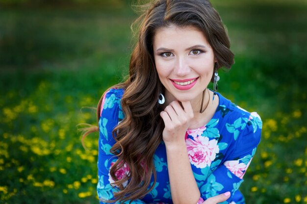 Brunette femme sourit dans une clairière estivale verte avec des fleurs