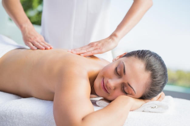 Brunette heureuse se faire masser au bord de la piscine