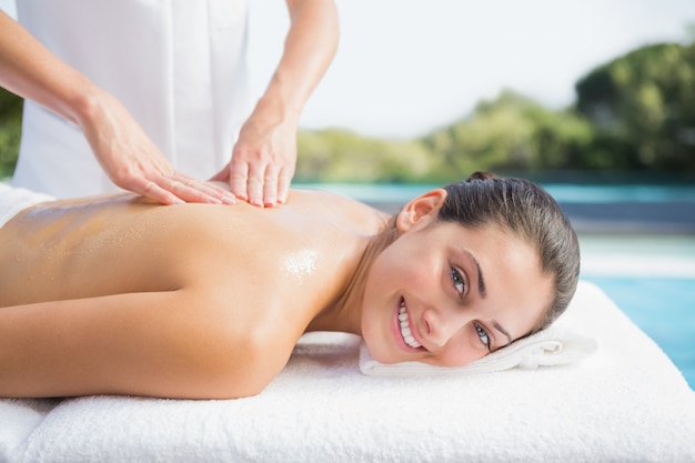 Brunette heureuse se faire masser au bord de la piscine