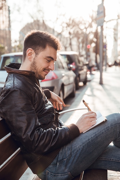 Photo brunette homme avec barbe écrit dans un cahier