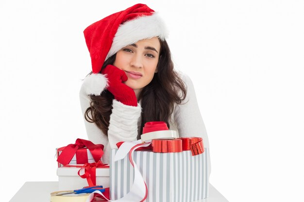 Photo brunette incertaine en cadeaux d'emballage de bonnet de noel