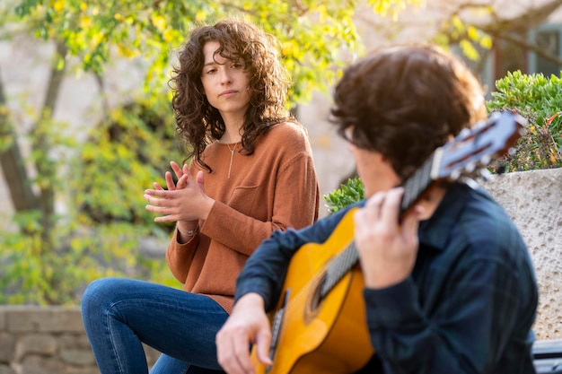 Brunette jeune femme bouclée chantant avec un homme guitariste dans la rue