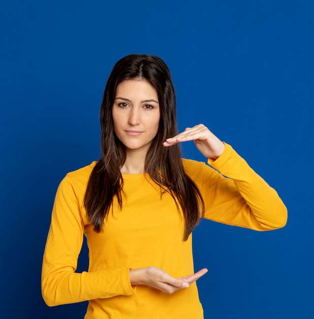 Brunette jeune femme gesticulant sur mur bleu