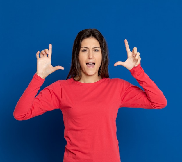 Brunette jeune femme gesticulant sur mur bleu