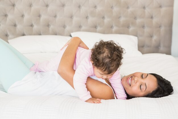 Brunette joue avec son bébé sur le lit