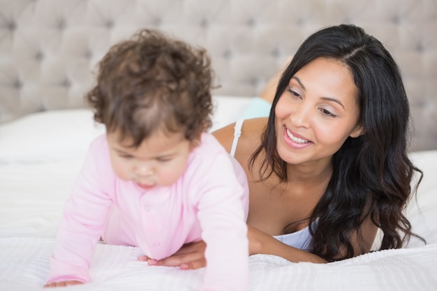 Brunette joue avec son bébé sur le lit